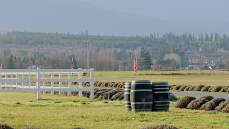 Pan-Right-Across-White-Fence-With-Barrels-On-Grass-And-Flags-Of-Britain-And-United-States-Lining-Road