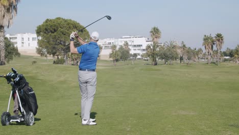 Real-time-rear-view-shot-caucasian-male-swinging-on-golf-course-in-Almeria,-Spain