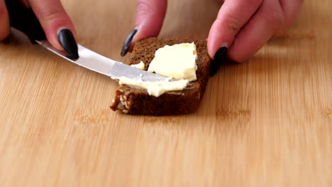 Spreading-A-Creamy-Butter-On-The-Slice-Of-Bread-In-The-wooden-Chopping-Board