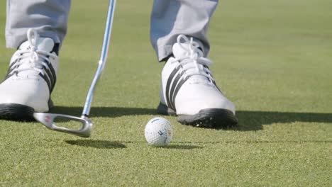 Close-up-motion-track-short-iron,-golfer-putting-golf-ball,-sunny-green-course