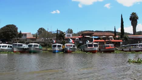 Geparkte-Boote-Mit-Wehenden-Mexikanischen-Flaggen,-Janitzio-See-Auf-Michoacan,-Mexiko