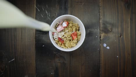 Unique-view-of-milk-being-poured-into-a-bowl-of-cereal-with-dried-strawberries