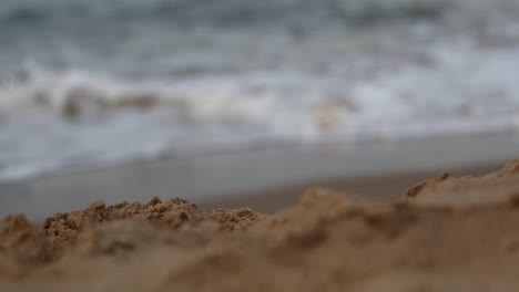 Focus-pull-from-slow-motion-waves-to-sand-in-foreground