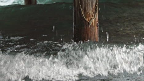 Waves-Crashing-Against-Wooden-Pole.-Low-Angle