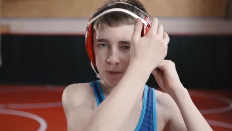 Teenage-wrestler-putting-on-his-headgear