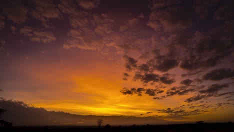 Atemberaubender-Sonnenaufgang-Im-Zeitraffer-über-Afrikanischen-Ebenen-Mit-Bergen-Und-Rotem-Himmel,-Beleuchtete-Wolken