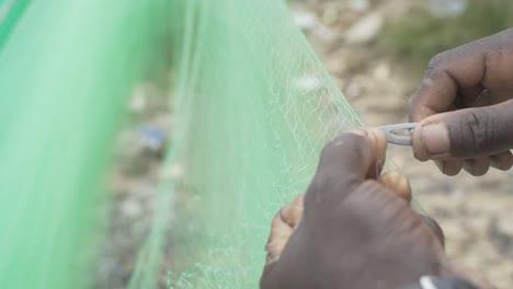 Die-Hände-Eines-Afrikanischen-Mannes,-Der-Ein-Fischernetz-Repariert