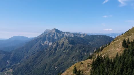 Aerial-view-of-a-mountain-range-in-Slovenia-surrounded-by-beautiful-green-pine-tree-forest