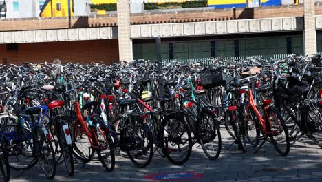 Bicicletas-Estacionadas-Frente-A-Una-Estación-Con-Un-Tren-Al-Fondo-En-Los-Países-Bajos