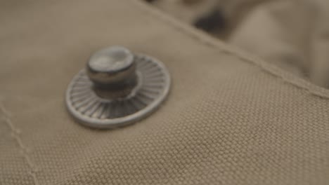 Macro-pull-out-of-a-metallic-button-on-a-coat