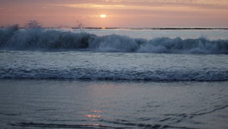 Sonnenaufgang,-Der-Sich-Auf-Dem-Wasser-Widerspiegelt,-Während-Eine-Welle-In-Zeitlupe-Herunterstürzt