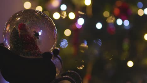 Schneeflocken-Treiben-Langsam-In-Der-Weihnachtsmann-schneekugel-Durch-Bokeh-weihnachtsbaumlichter
