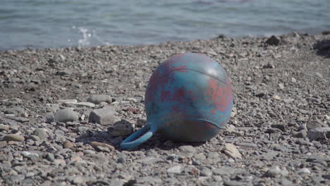 Marine-garbage-buoy-washed-ashore-on-beach,-human-litter-impact