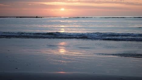 Sonnenaufgang-Spiegelt-Sich-In-Wellen-Wider,-Die-In-Zeitlupe-Auf-Einen-Ruhigen-Strand-Treffen