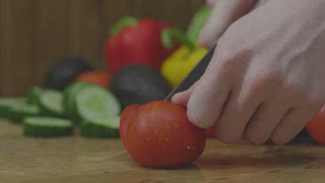 Dull-knife-slips-while-cutting-whole-tomatoes-into-slices,-Closeup-on-Hands