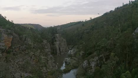 Drone-Hacia-Atrás-Sobre-Un-Río-Idílico-En-Portugal-Rodeado-De-Exuberantes-Montañas-Rocosas