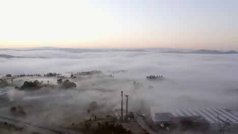 Aerial-view-of-a-foggy-day-with-low-clouds-over-an-industrial-area-with-a-highway-in-Portugal