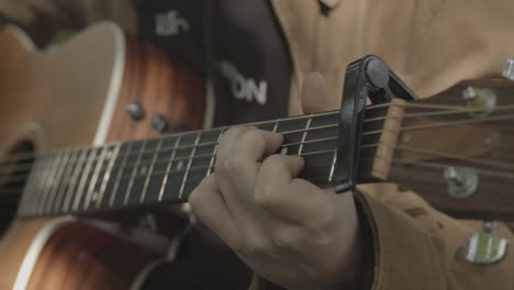 Young-Man-Sings-and-Plays-Acoustic-Guitar,-Closeup-Tilt-Down-from-Face-to-Hands