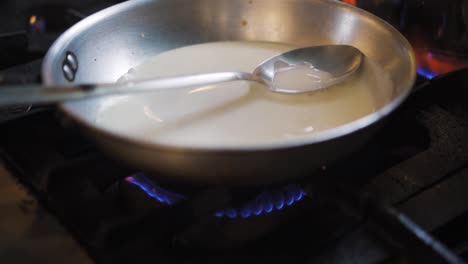 Chef-Put-Saucepan-With-Cream-And-Milk-Over-Medium-Fire-By-Gas-Stove-Burner