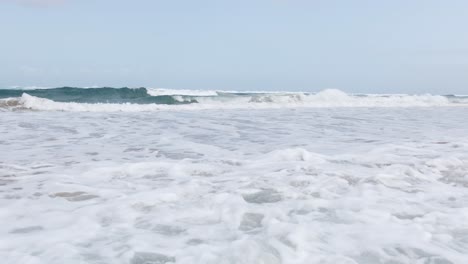 Waves-coming-onto-a-beach-creating-sea-foam