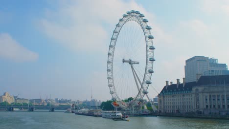 The-London-Eye-not-moving-and-completely-static-over-the-Thames-River-reflecting-the-summer-sun-in-slow-motion,-during-the-Coronavirus-lockdown-pandemic-2020