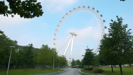 The-London-Eye-reveal-under-tree's-in-Jubilee-Park-on-a-blue-skies-summer's-day