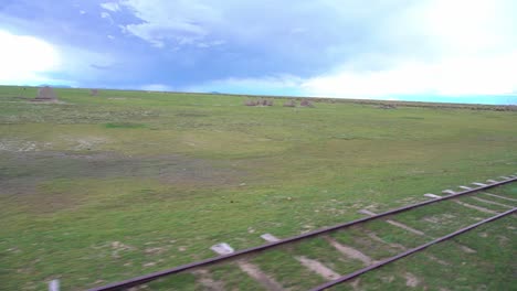Daytime-shot,-real-time-passing-railroad-track,-relaxing-green-field,-blue-sky-horizon