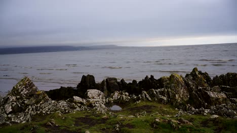 View-of-sea-waves-in-ocean-,-green-grass-and-rocks-in-Dundalk,-Ireland