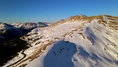 Luftschwenkaufnahme-Von-Wunderschönen-Bergen,-Die-Während-Der-Goldenen-Stunde-Mit-Schnee-Bedeckt-Sind