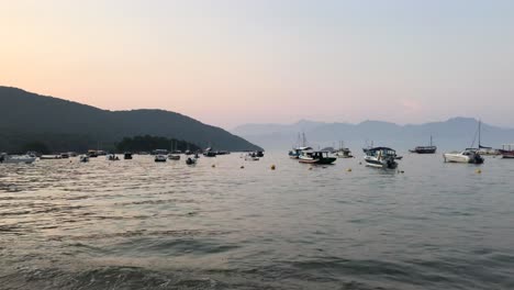 Boats-bobbing-in-bay-with-sunset-over-mountains-in-background