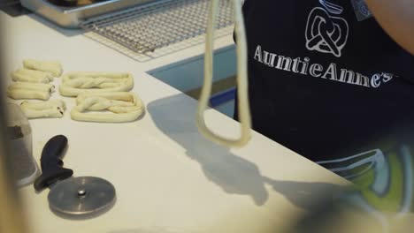 Person-Twisting-And-Forming-Raw-Dough-Into-Pretzels---high-angle,-slow-motion