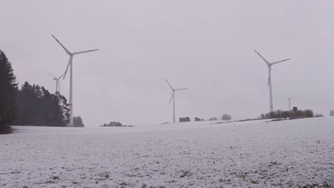 Three-wind-turbines-roating-in-a-snowy-white-winter-landscape
