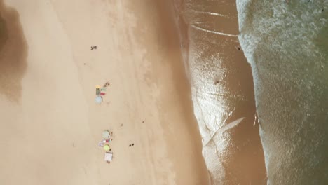 Forward-moving-and-upward-panning-birdseye-drone-shot-above-the-shoreline-in-Tofo,-Mozambique