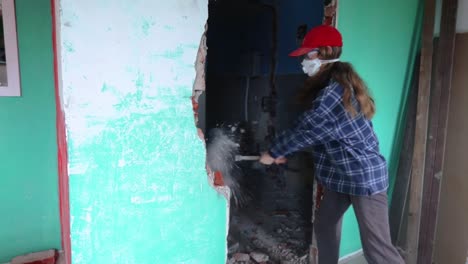 Woman-Wearing-Face-Mask-Demolishing-Concrete-Wall-Using-Sledgehammer---medium-shot