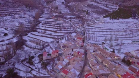 Drone-panning-up-on-a-high-mountain-with-a-spanish-village-covered-in-snow