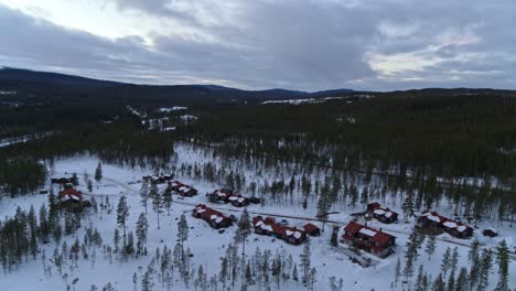 Dolly-shot-of-a-drone-flying-over-the-wintry-landscape-of-the-little-village-Fulufjallsbyn-in-northern-europe,-Sweden