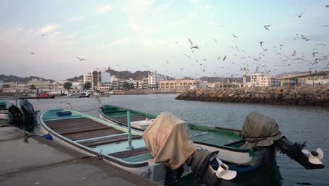 Fischerboote,-Die-Auf-Einem-Dock-Geparkt-Sind,-Mit-Möwen-Und-Vögeln,-Die-In-Mutrah-überfliegen