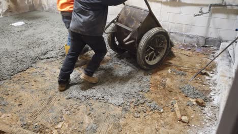 two-people-wheel-Barling-cement-into-room-to-repair-floor