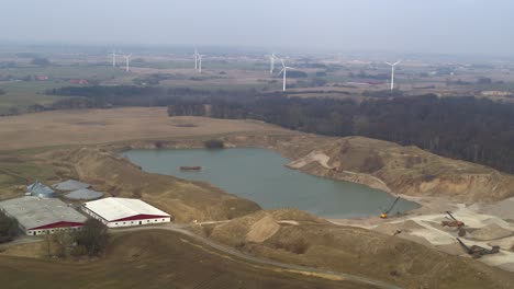 Aerial-of-a-pond-with-cranes-and-wind-wheels-in-the-background