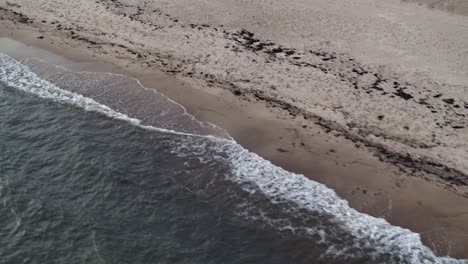 Lateral-drone-flight-over-the-sea-with-a-view-of-the-sand-beach-with-waves