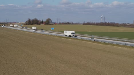 Drones-fly-over-a-field-next-to-a-freeway-with-traffic-in-spring