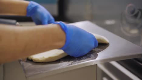 Bäcker-Mit-Handschuh-Legte-Teig-In-Die-Glättmaschine-In-Der-Küche