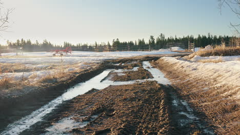 Smooth-push-over-muddy-frozen-dirt-road-leading-towards-farm-gate