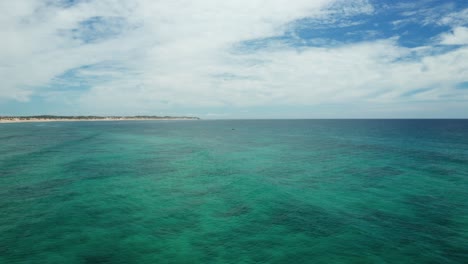 Drone-shot-over-a-calm-and-clear-ocean-in-Tofo,-Mozambique