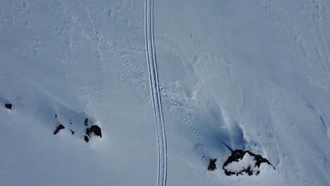 Top-down-birds-eye-view-aerial-shot-of-sled-tracks-and-footprints-in-the-snow