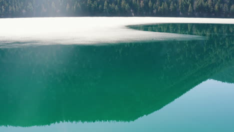 Aerial-orbit-of-mountain-reflection-in-a-semi-frozen-lake