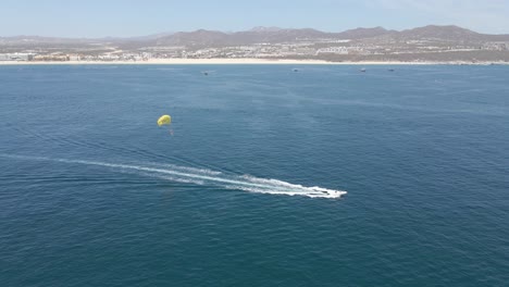 Aerial:-tourists-parasailing-off-coast-on-summer-vacation