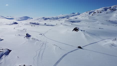 Beautiful-aerial-drone-shot-of-man-driving-snowmobile-in-arctic-snowy-landscape