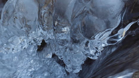 Detailaufnahme-Des-Im-Winter-Fließenden-Flusswassers-Mit-Kristallenen-Eiszapfen-An-Der-Seite
