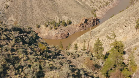 Aerial-reveal-over-desert-mountain-of-muddy-river-in-valley-below